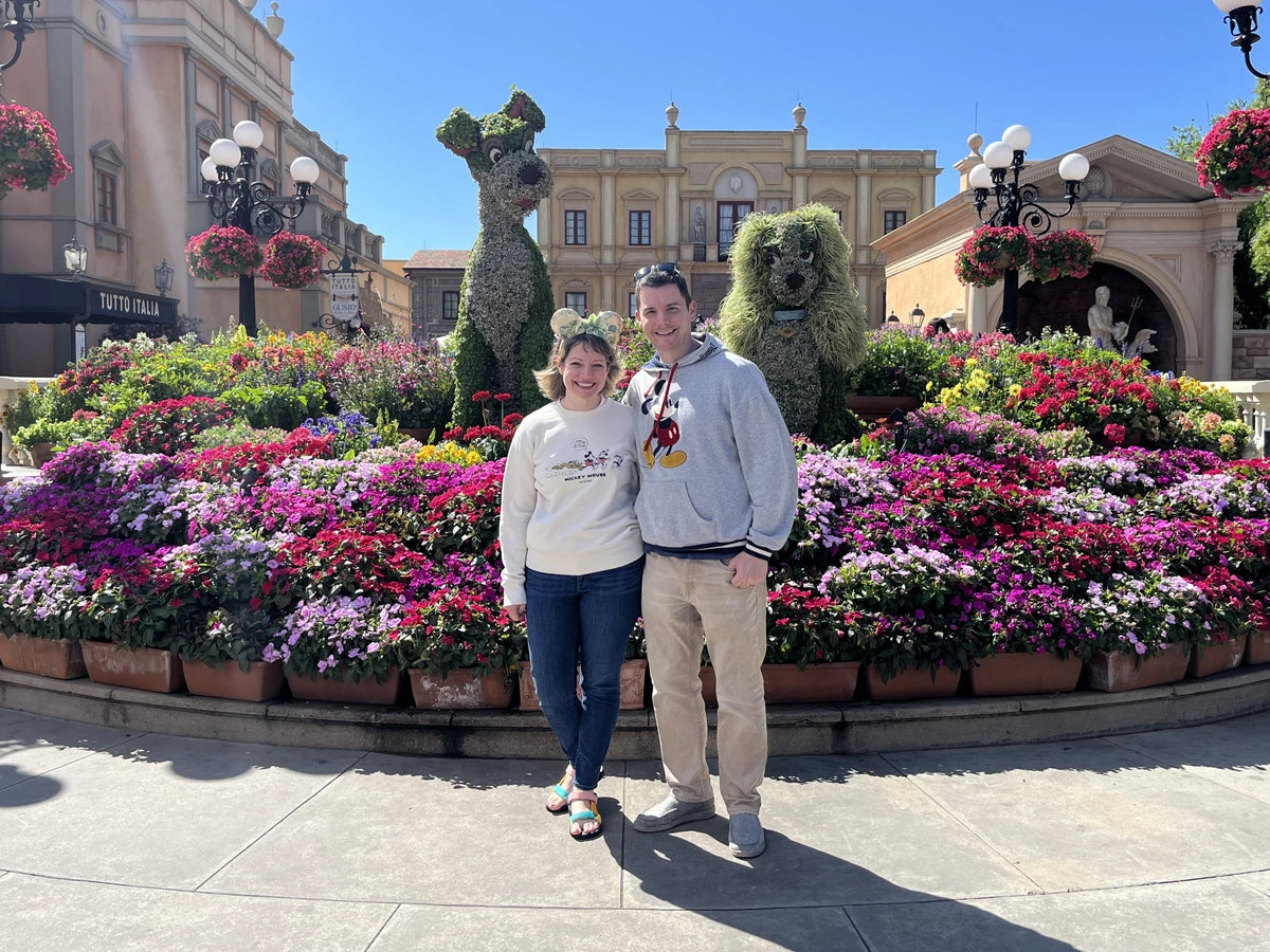 Chris and Laura among flowers and Lady and the Tramp topiaries at EPCOT