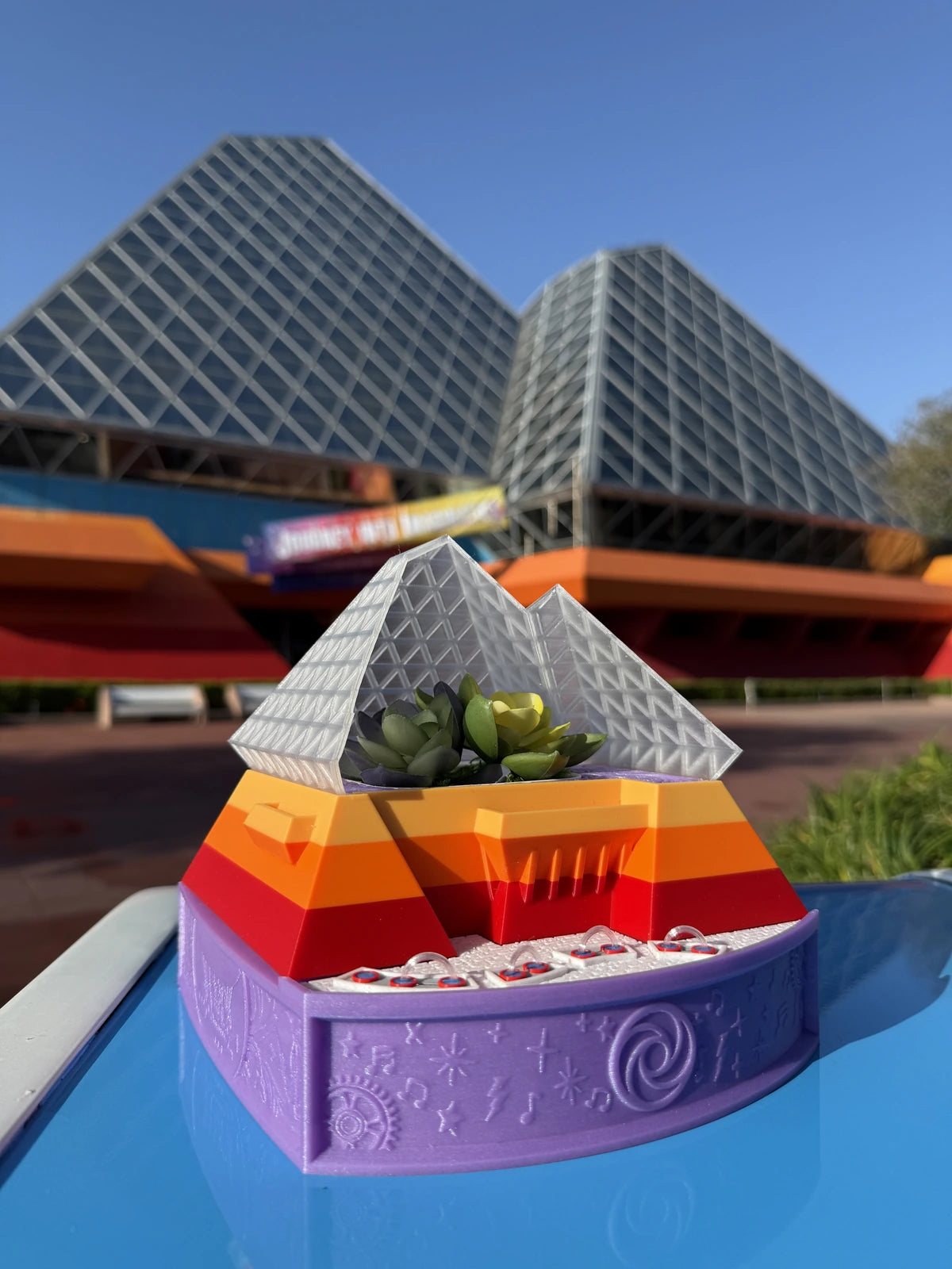 Imagination Planter with silver pyramids, orange and red walls, and a purple base in front of the Imagination pavilion