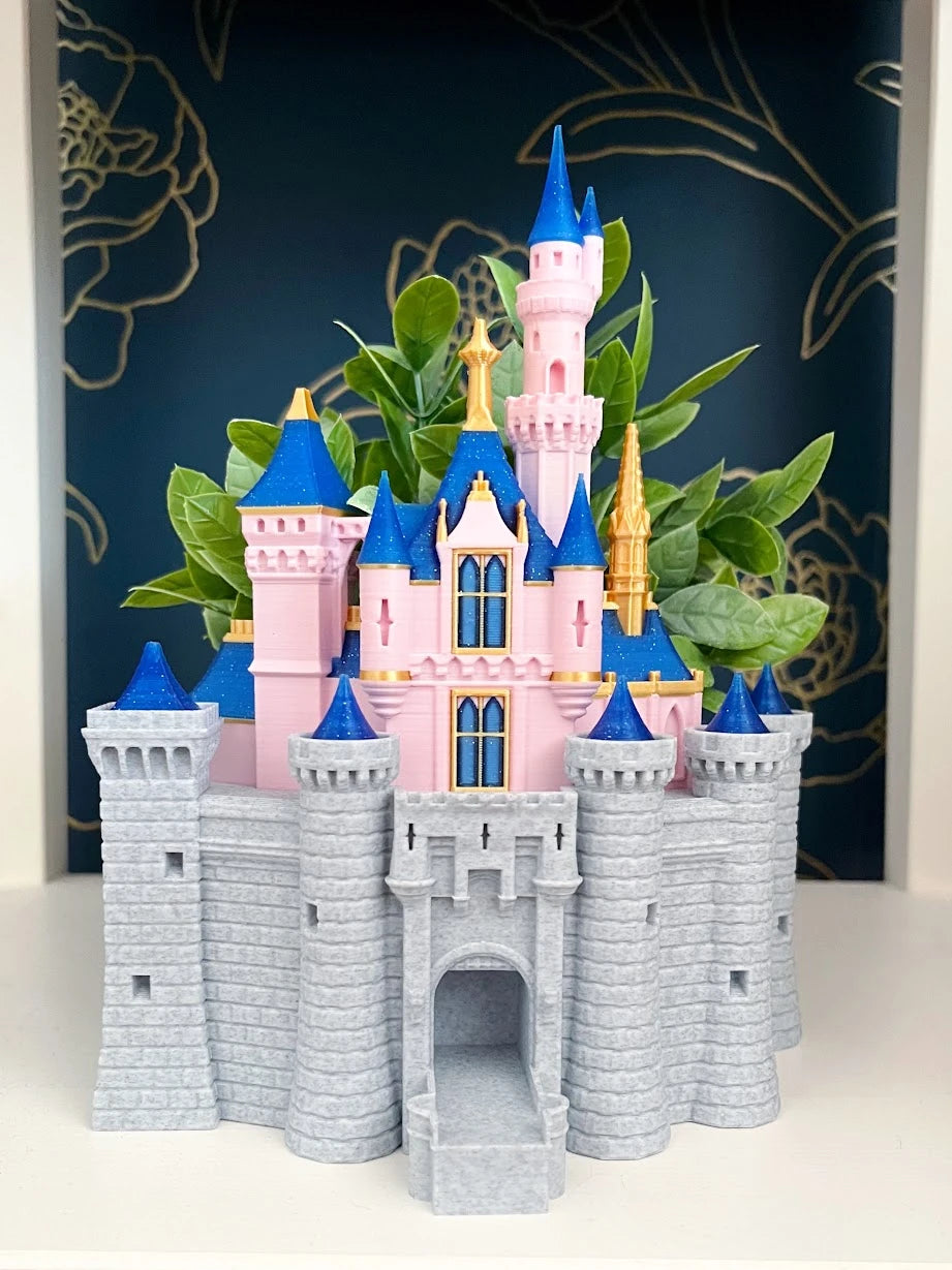 Walt’s Castle planter with blue and gold turrets, a pink tower, and greenery against a dark floral backdrop